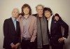 Los Rolling Stones posan sonrientes ante un fondo blanco que destaca sus arrugas de viejas glorias del rock and roll