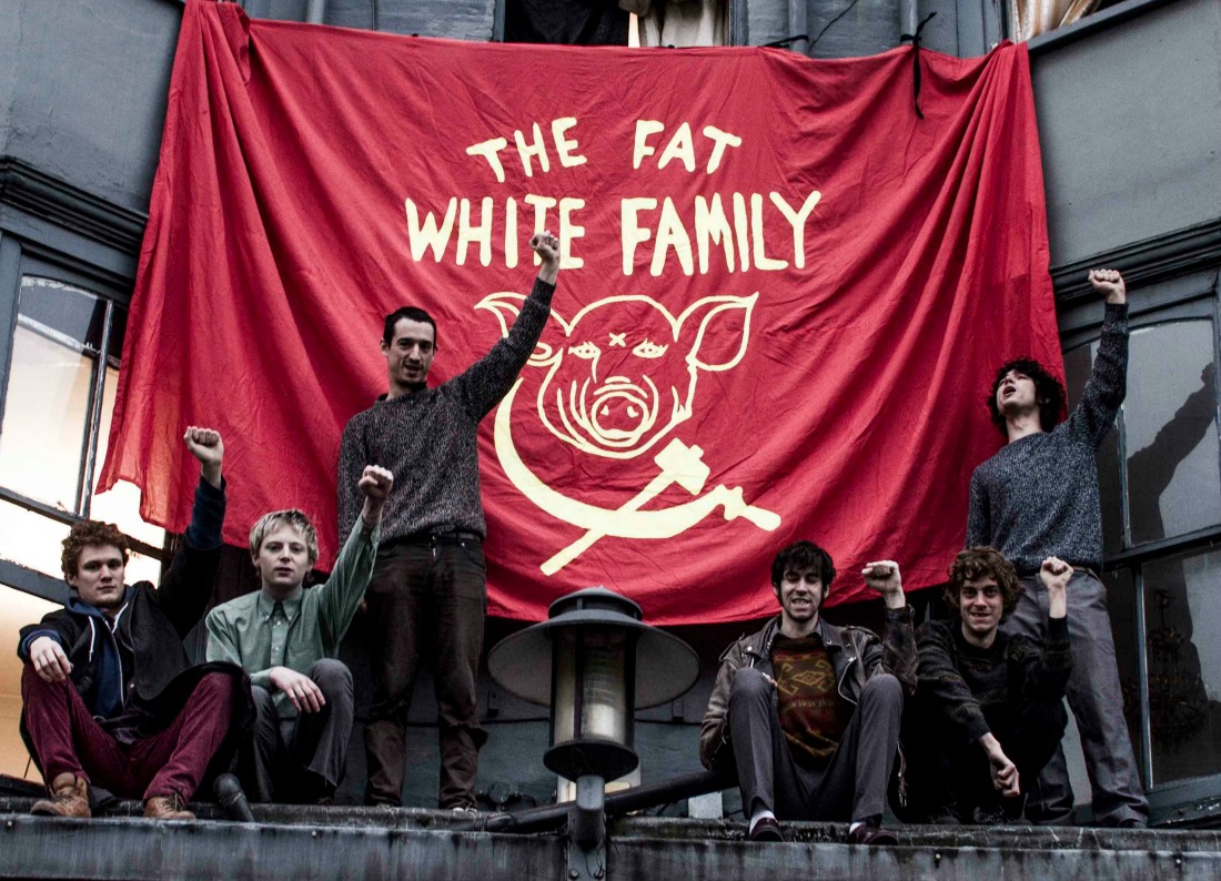 The Fat White Family alzan el puño junto a su bandera roja.