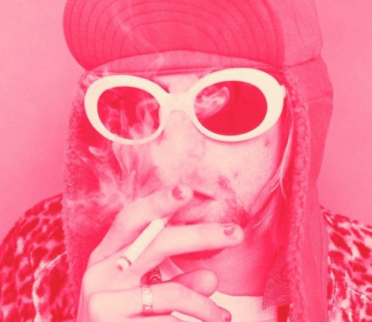 Kurt Cobain con gafas de sol blancas, un gorro y fumando, con un filtro rosa