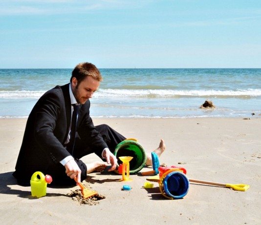 Hombre de negocios jugando en la playa.