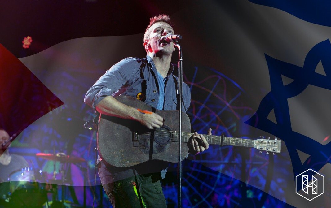 Chris Martin toca la guitarra en directo entre las banderas de Palestina e Israel.