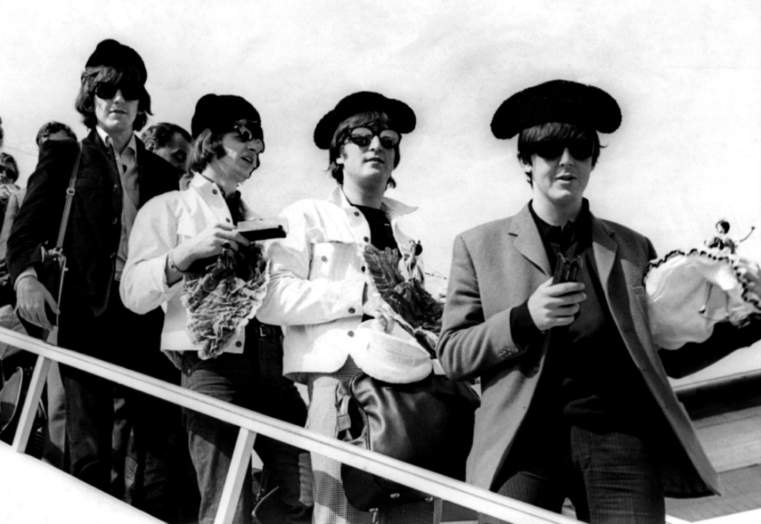 The Beatles bajando de un avión en España con montera.