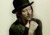 Thom Yorke con un sombrero se pone la mano en la cara.