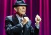 Leonard Cohen con un micrófono frente a un telón morado